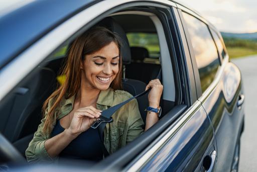 AAA Auto Insurance - Smiling lady buckling aseat belt in her car.